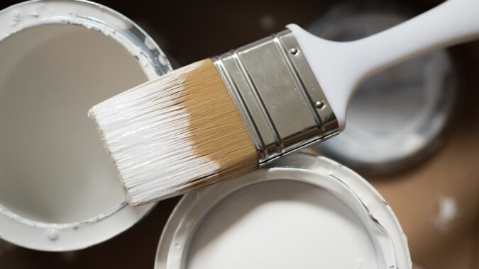 tin of white paint with paint brush.